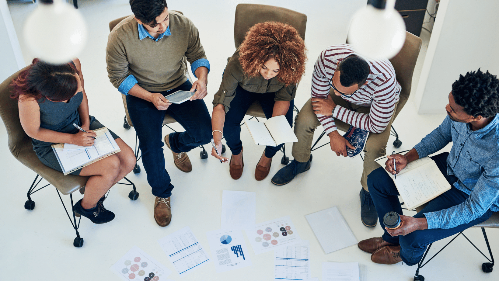 Ascend Adwerks' team of people sitting around a table with papers represents Data in Ascend Adwerks' 3E Advancement Model.
